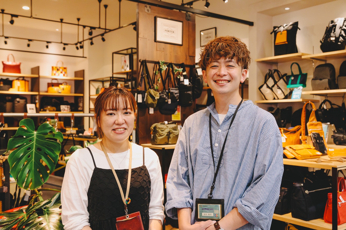 バッグに囲まれたお店で明るく働く社員さん